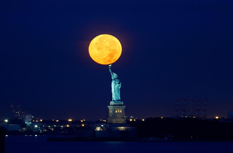 Суперлуние-2015. Луна прячется за зданием Статуи свободы, Нью-Йорк, 2015 г. ©Гари Хершорн/Corbis